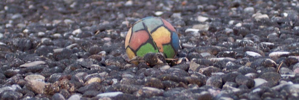 multicoloured but faded rubber football on pebbles; photo