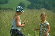 Girls in hay meadow with flowers and panama hat