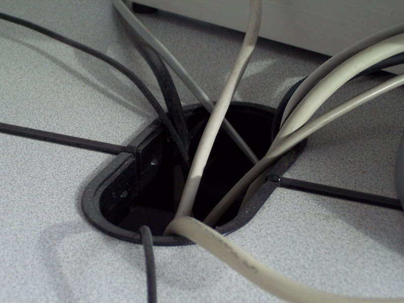 Kabel greifen aus dem Kabelschacht eines Computertisches; Foto
